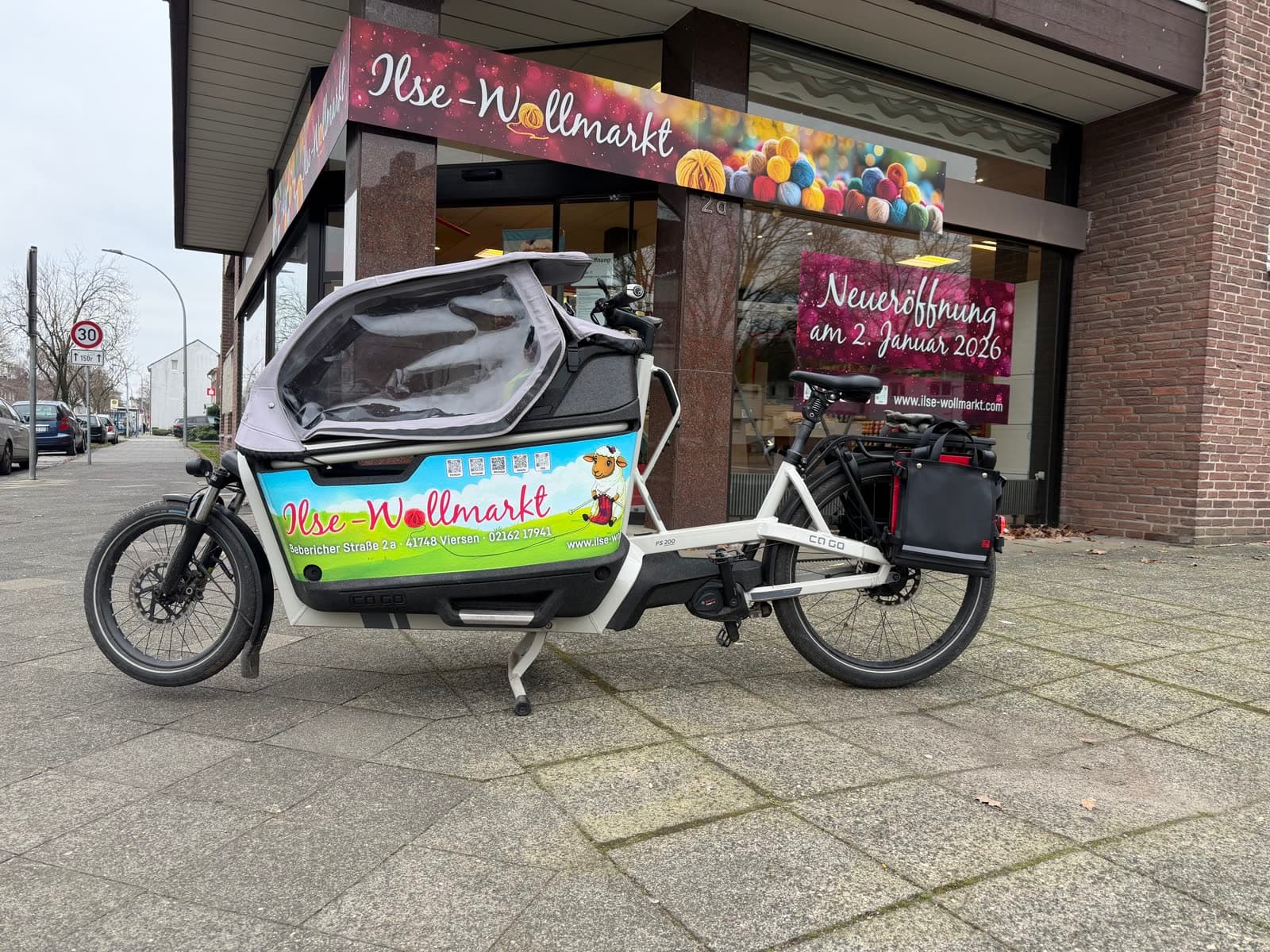 Das Schaufenster des Ilse Wollmarkt an der Bebericher Straße 2a, davor das Lastenrad des Ladens